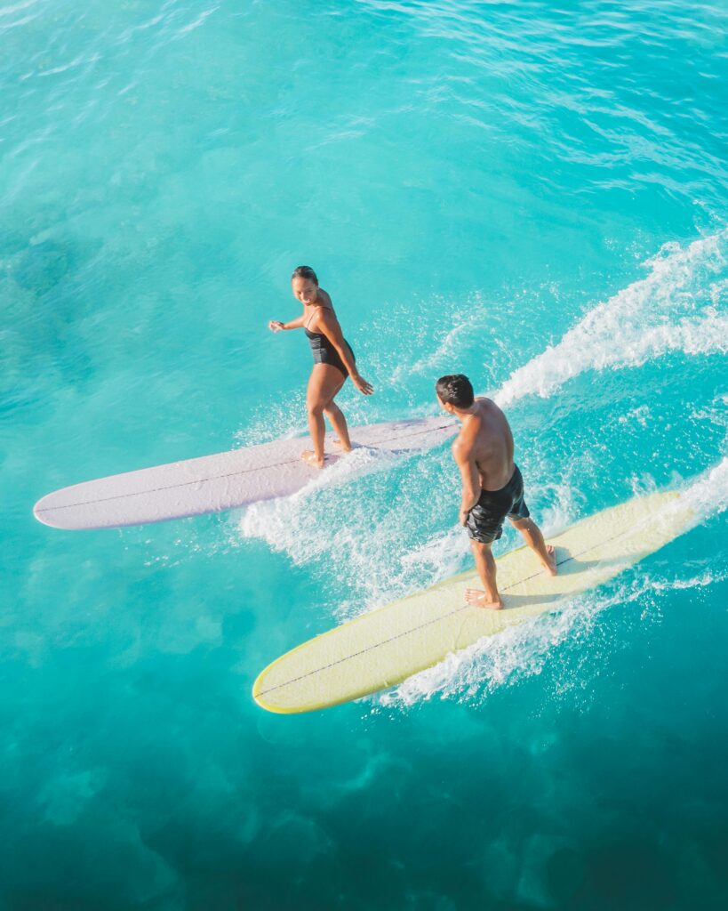 Aula avulsa de surf em Ubatuba com instrutor experiente Surfistas em Ubatuba deslizando sobre ondas em aula avulsa de surf com acompanhamento profissional